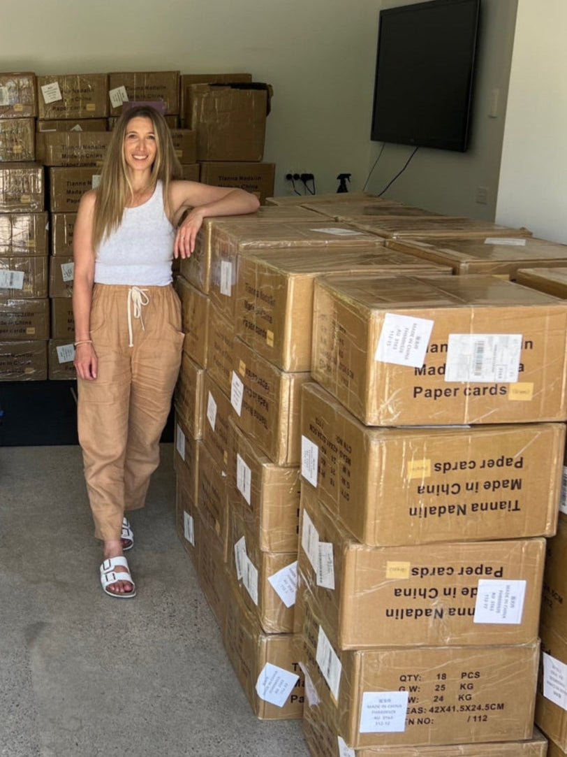 Major Tones founder Tianna Nadalin standing in garage with dozens of boxes of her first delivery of Major Tones games